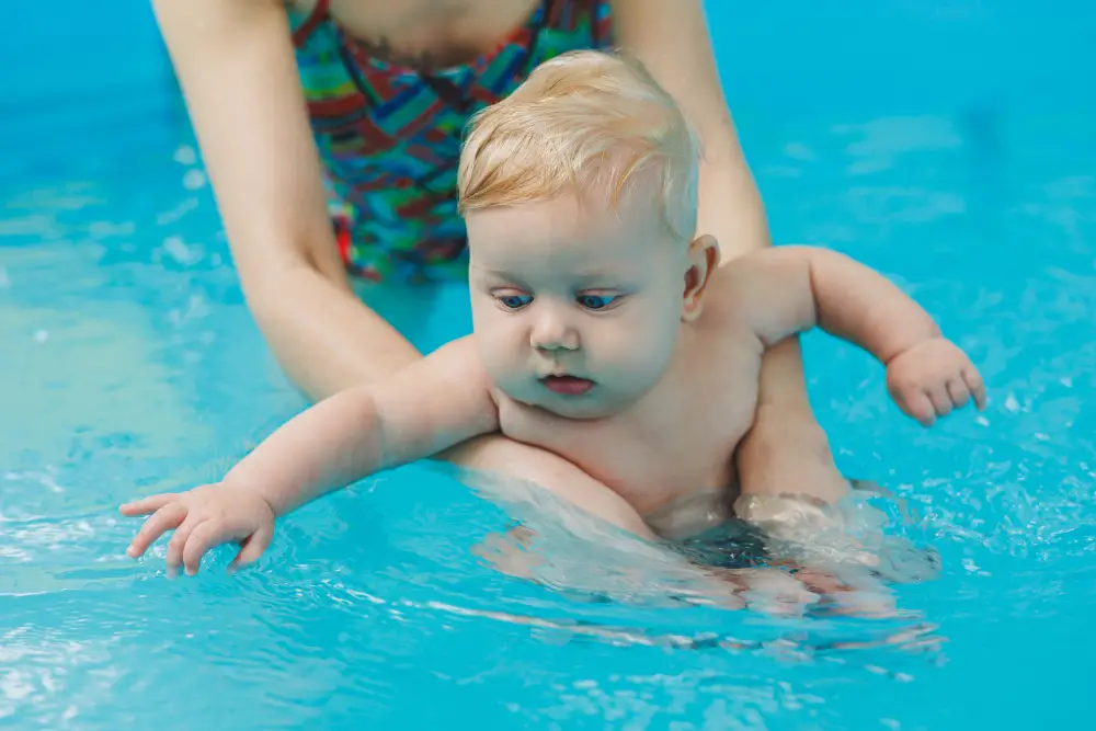 Bond and Swim with Your Little One A 6-month-old baby learns to swim with a coach in the pool. Swimming pool for babies. Children's development