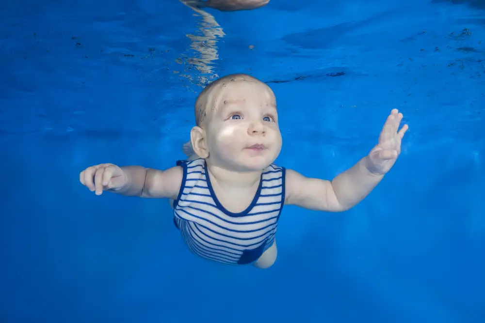 Mini Star 2_ 9 months - 19 months Little boy in a striped suit swim underwater on a blue water background. Healthy family lifestyle and children water sports activity. Child development, disease prevention