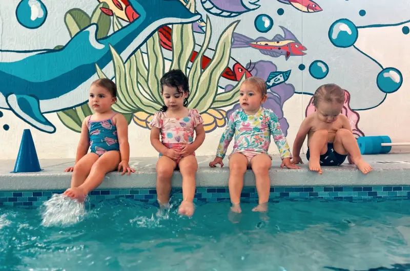 Main Page- Group Classes Group lessons - kids splashing at the side of the pool